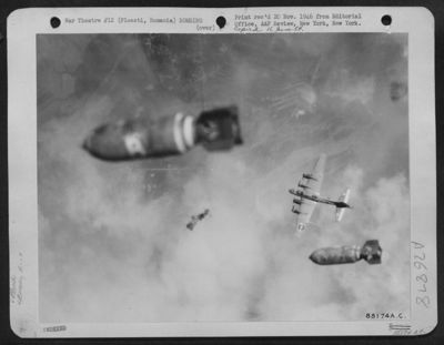 This remarkable photograph, taken during the Boeing B-17 attack on the Ploesti oil refineries in Rumania on 15 July 1944, shows bombs falling on the target from the formation flying above this B-17 and flak bursts from anti-aircraft defenses. Smoke