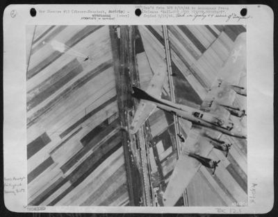 Two members of a Boeing B-17 Flying Fortress crew "hit the silk" after their bomber is hit by flak over the aircraft assembly plant at Wiener-Neustadt, Austria. Shortly after the picture was made the rest of the crew bailed out and the plane
